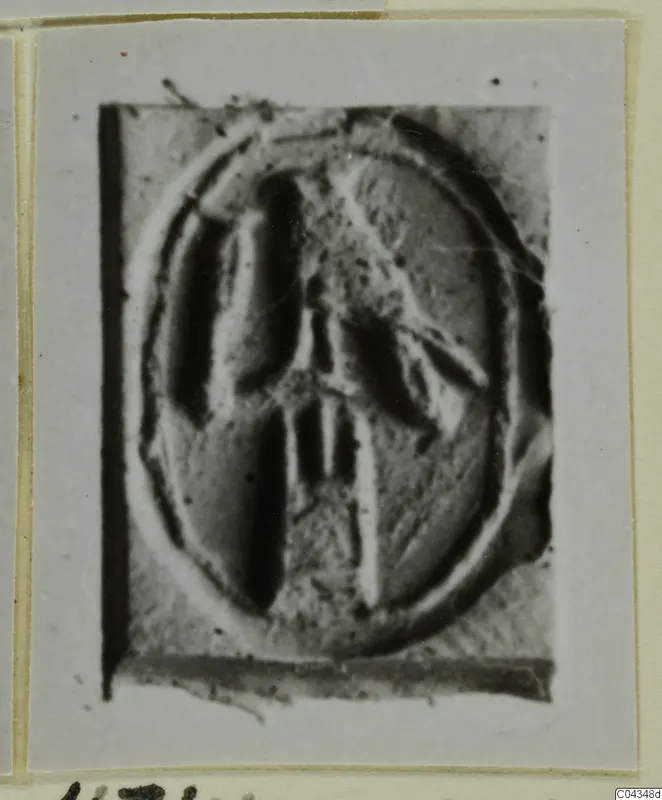 Oval seal or gem face with a raised central motif, photographed on a mounted card