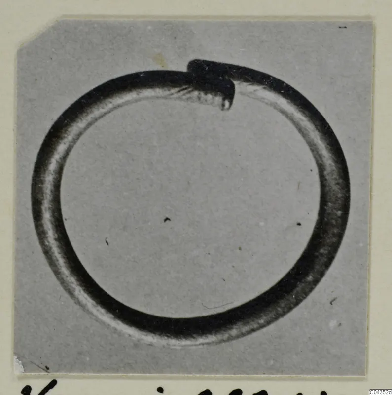 Silver ring from Vouni with one end overlapping the other, photographed on a grey backdrop