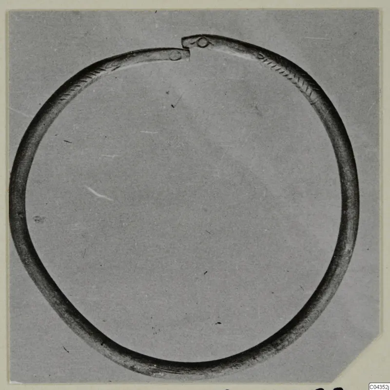 Open silver ring with incised chevron pattern on the band and knobbed ends, photographed on grey card