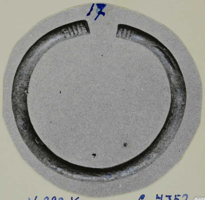 Silver bracelet, an open ring with ribbed ends, shown on a round grey card