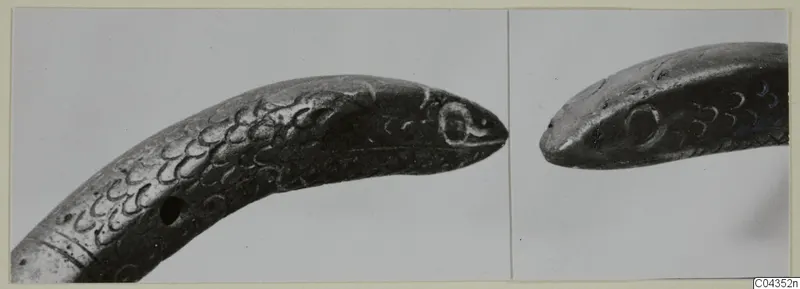 Two views of a silver-grey metal object ending in a snake's head, with incised scale pattern
