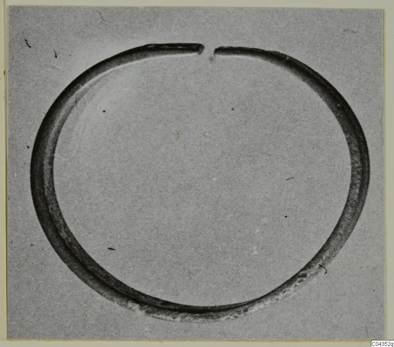Open silver ring or bracelet with a gap at the top, photographed alone on a grey background