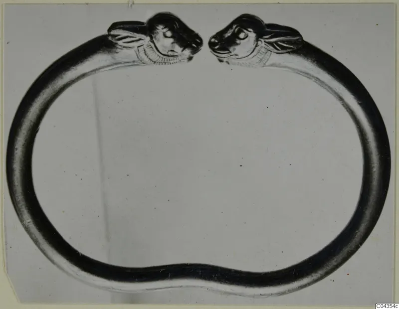 Open ring of smooth metal with an animal head at each end, facing the gap, shown against a plain background.