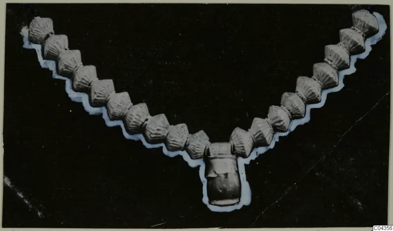 Necklace of ribbed beads with a central pendant, from Arsos, shown against a black background