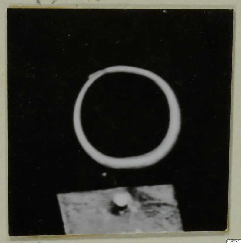 Find photograph of a single plain ring on a black background, with a small grey stand below