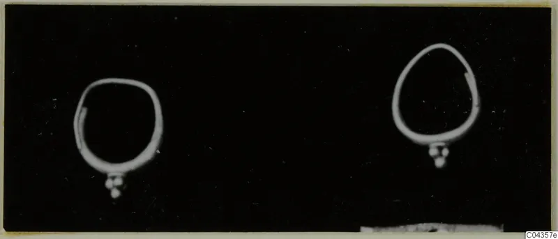 Two gold rings with small bead clusters hanging from them, photographed against black; Lapithos, Kastros tombs.