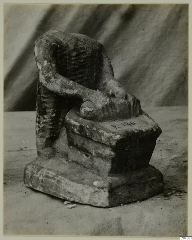 Limestone figure of a seated, headless person with one arm resting on a stepped base