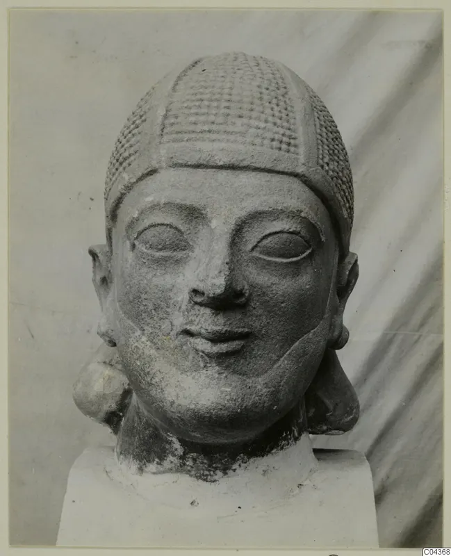 Limestone Neo-Cypriote head with a cross-hatched cap and large eyes, shown on a plain block base