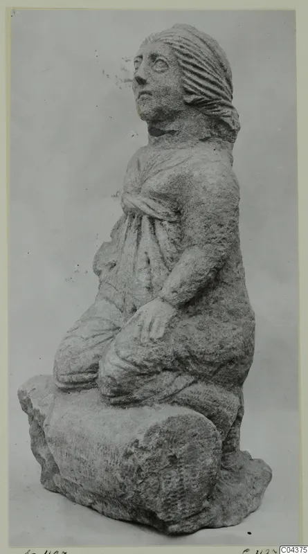 Stone statue of a kneeling female figure from Soli, head turned to the side, hair pulled back.
