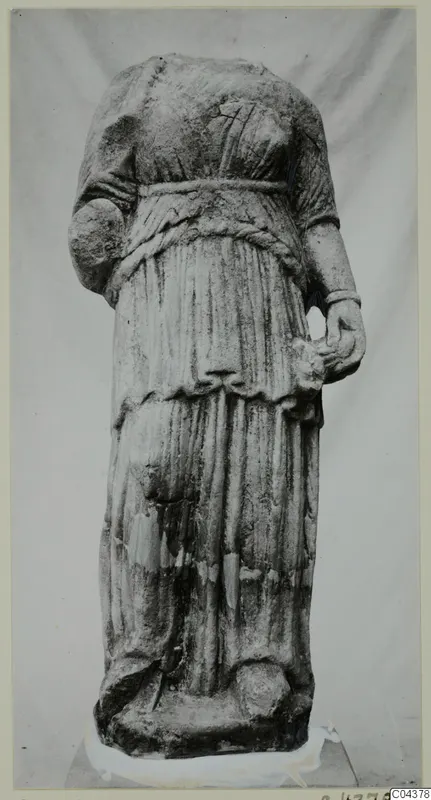 Headless marble statue of a draped standing female figure from Soli, photographed against a plain backdrop.