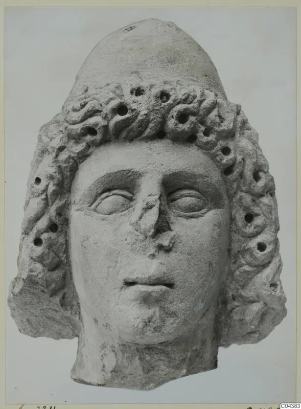 Limestone head of a figure with a tall rounded headdress and curled hair, from Soli