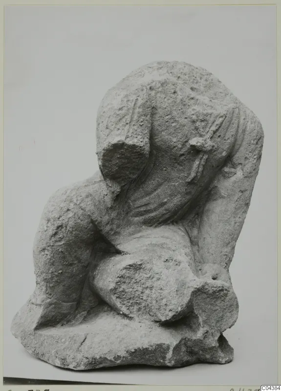 Stone sculpture from Soli: a headless, crouching draped figure carved from pale, pitted stone.