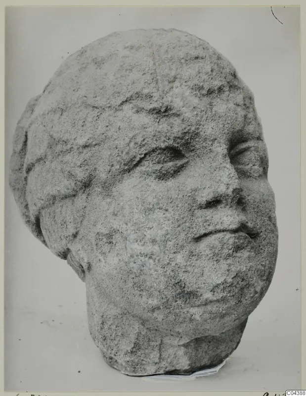 Carved stone head from Soli, shown in three-quarter view against a plain background