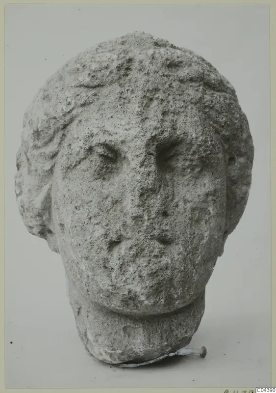 Carved stone head of a man with curly hair and a worn face, from Soli