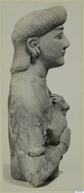 Terracotta bust in profile facing right, with incised hair and hands holding a small rounded form at the chest