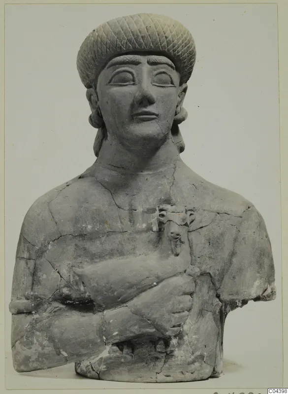 Terracotta Neo-Cypriote bust of a figure in a tall patterned cap, holding a vessel with an animal head against its chest
