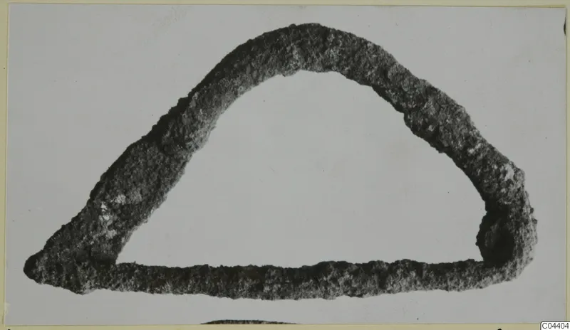 Corroded bronze loop, rounded triangular form, shown alone on a pale background