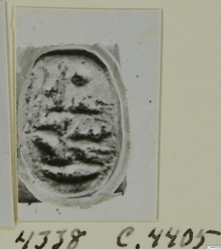 Oval seal or gem from Ayia Irini with dark horizontal grooves on its face, shown on a card mount