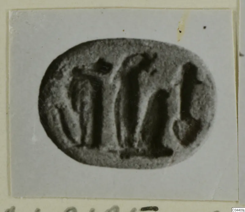Engraved oval stone seal with a row of dark carved figures, shown on a grey card mount