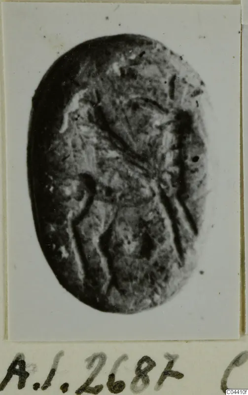 Oval dark stone seal or gem with incised lines, photographed face-on and mounted on a card