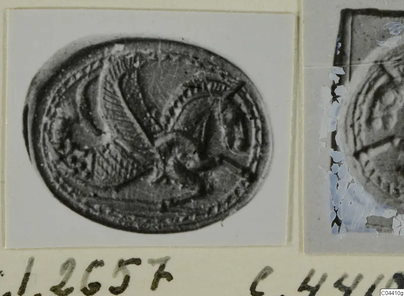 Glyptic from Ayia Irini: oval engraved seal stone with a wing-like figure and beaded border, mounted on a card.