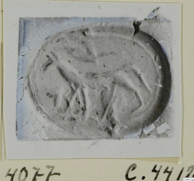 Oval seal or gem with a faint carved design, shown as a photograph mounted on a card.