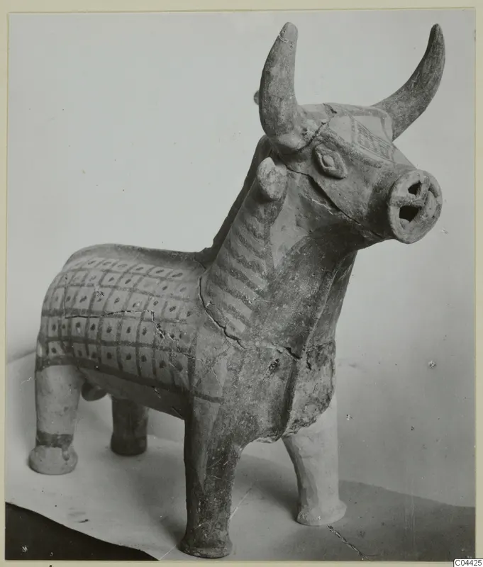 Terracotta figurine of a bull with upturned horns, an open muzzle and a painted grid pattern on its body.