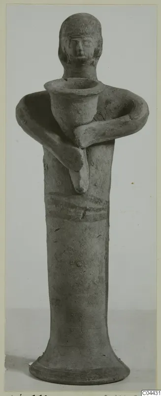 Terracotta figurine of a standing figure holding a cup-shaped vessel at its chest, on a flaring base