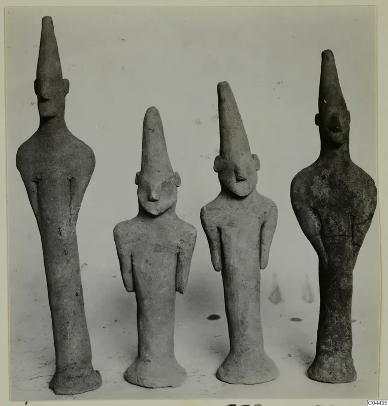 Four terracotta figurines with tall, pointed heads standing side by side