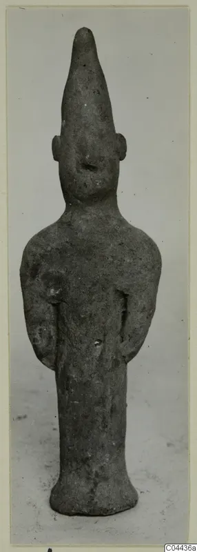 Terracotta figurine of a standing figure with a tall pointed head and arms held close to the sides.