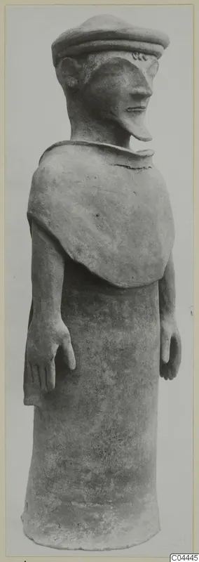 Standing terracotta figure with a flat cap and long pointed nose, shown in side view against a pale backdrop