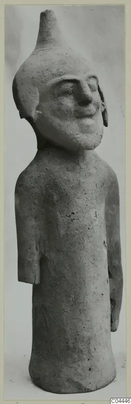 Terracotta figurine from Ayia Irini: a standing figure with a tall conical head and a broad smiling face.