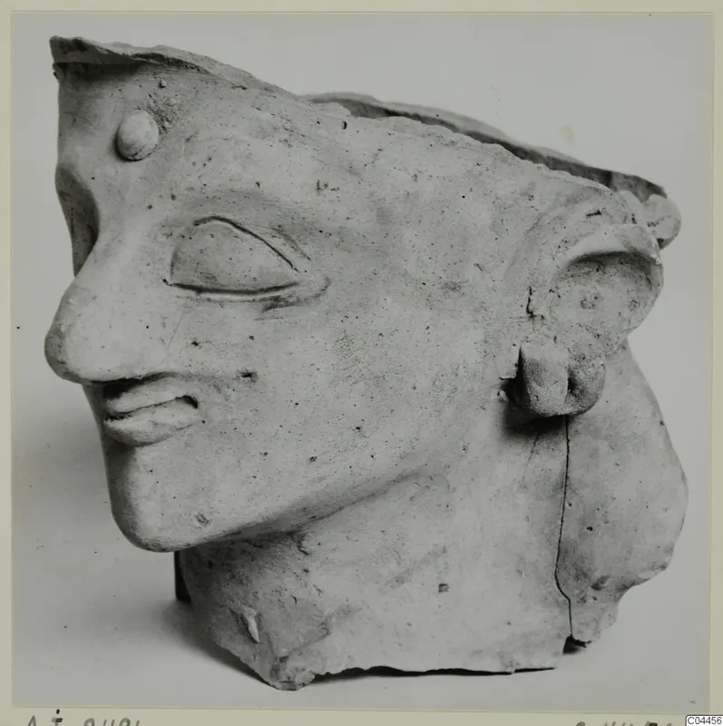 Terracotta head fragment from Ayia Irini, shown in profile facing left, with the top edge broken away