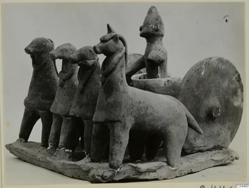 Terracotta group of four animal figures harnessed to a cart with a disc wheel and a standing human figure, on a flat base