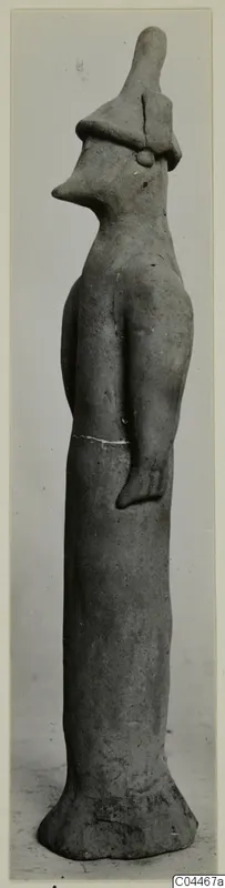 Terracotta figurine of a standing figure with a tall hat-like cap and a pointed, beak-like face