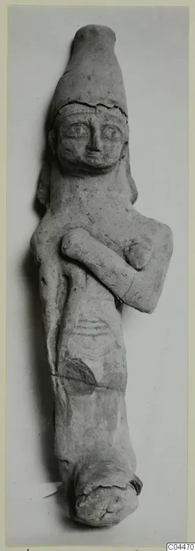 Terracotta figurine with a tall cylindrical headdress and one arm folded across the chest, photographed against a grey backdrop.