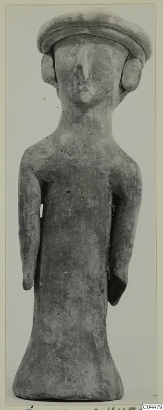 Terracotta figurine of a standing figure with a broad flat cap-like head and arms held at its sides.