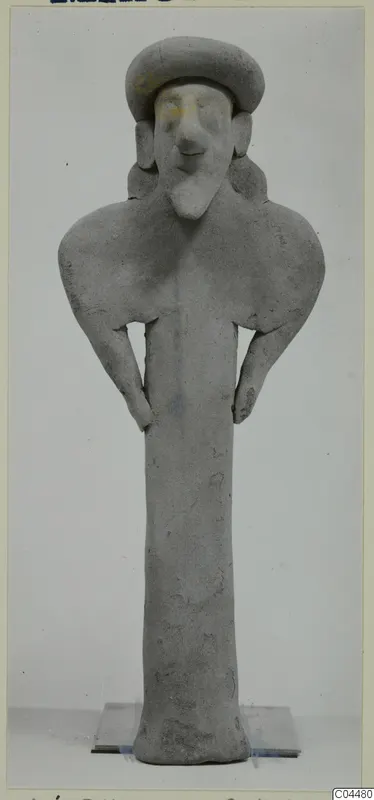 Grey terracotta figurine of a standing figure with a broad cap-like head and hands resting on the hips