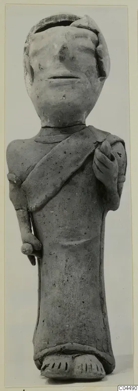 Standing terracotta figurine with a diagonal band across the chest and a broken top to the head