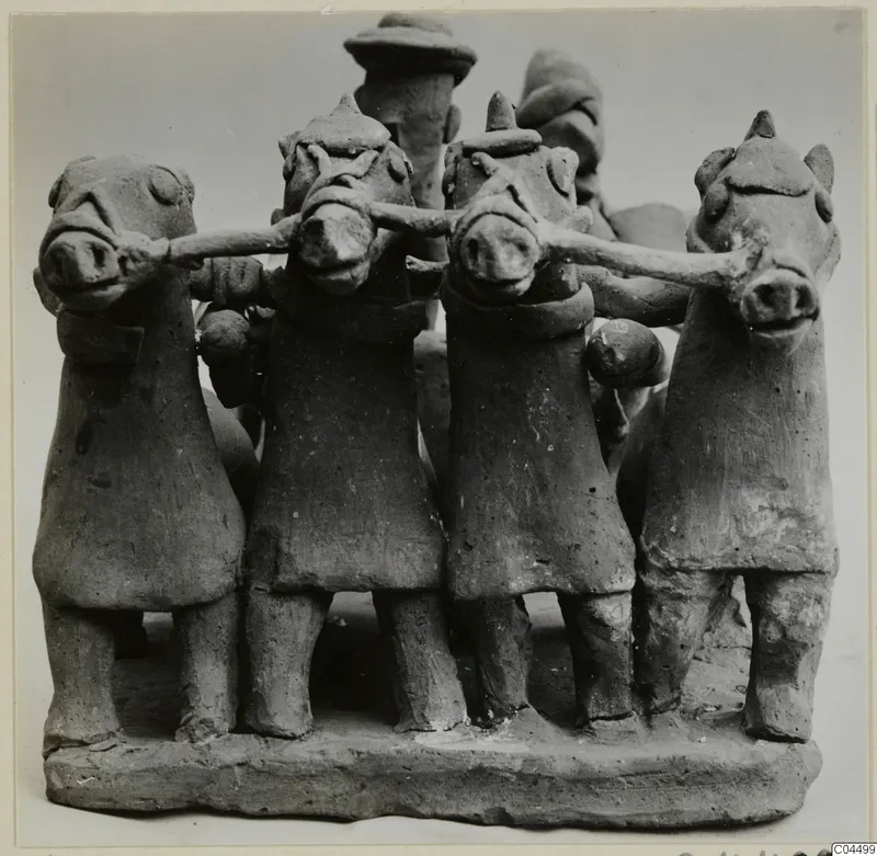 Terracotta group of four small standing figures with animal-like heads, arms linked, on a rectangular base