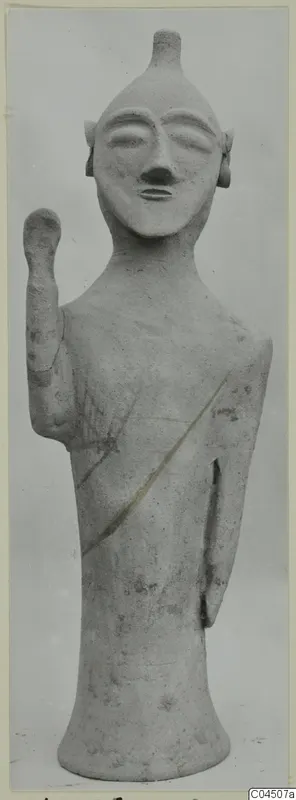 Terracotta figure with a raised arm and a dark diagonal band across the body, from Ayia Irini