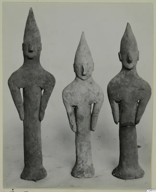 Three terracotta figurines of standing figures with tall pointed heads and arms held at their sides.