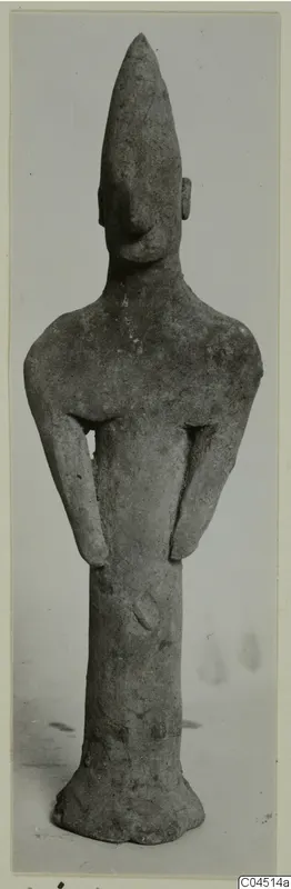 Terracotta figurine of a standing human figure with a tall pointed head and arms bent at the sides.