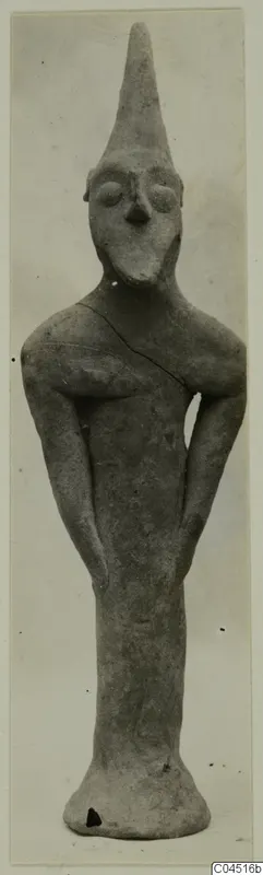 Terracotta figurine from Ayia Irini with a tall conical head and bent arms, standing upright