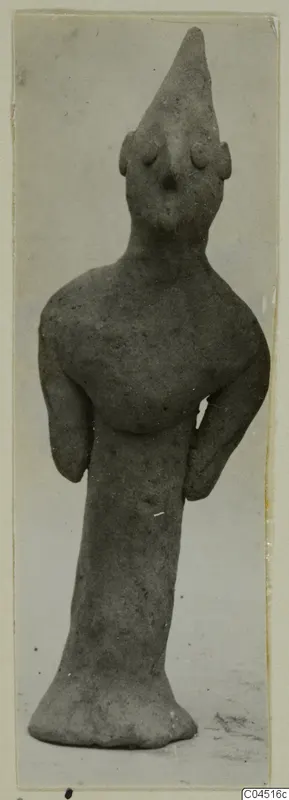 Terracotta figurine from Ayia Irini with a tall conical head and bent arms, standing on a flared base