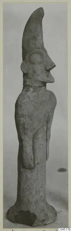 Terracotta figurine standing upright, with a tall tapering headdress and a large round eye in relief.