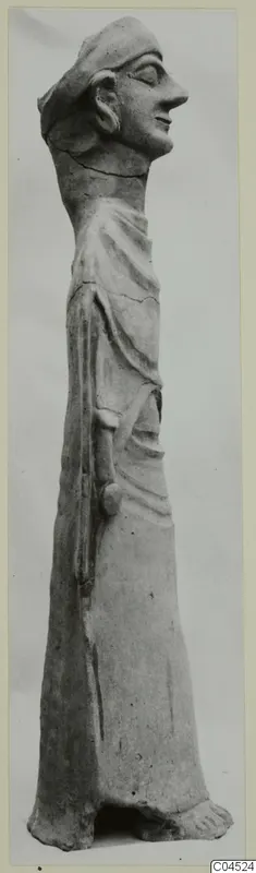 Terracotta standing figure in profile facing right, wearing a cap and a draped garment, with one arm bent at the waist.