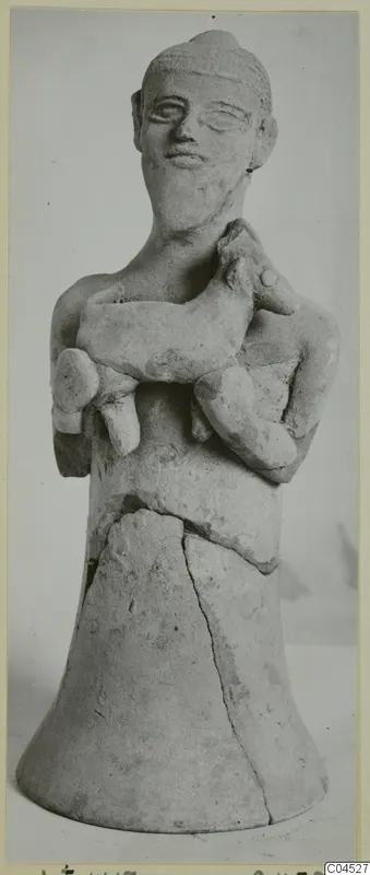 Terracotta figurine of a standing human figure holding a small animal against its chest, on a flared base