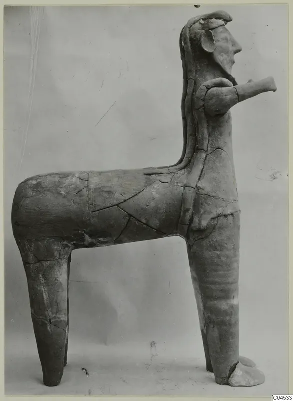 Terracotta figure with a human-like head on an animal-like body, shown in side view against a plain grey background.