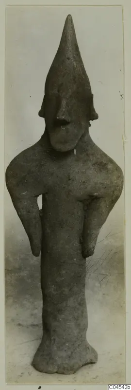 Terracotta figurine with a tall pointed head and long arms held out from the body, from Ayia Irini